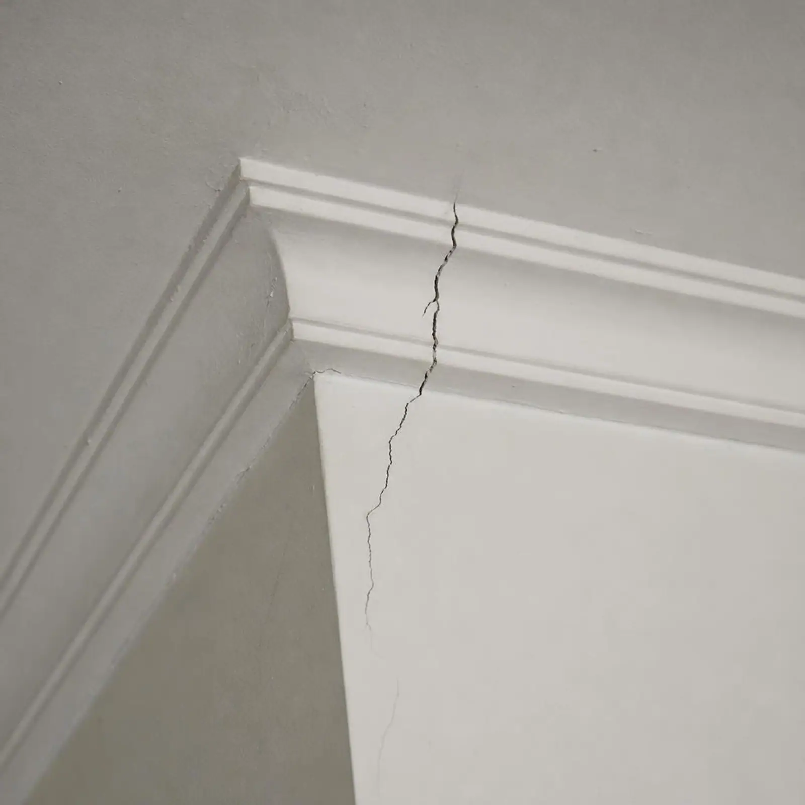 Crack running through a plaster cornice where the wall meets the ceiling